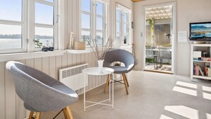 A modern living room with large windows, a fireplace, a television, and a view of the outdoors. - "Drifa" - 20m from the sea by Interhome (Hejls)