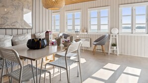 A modern dining area with a wooden ceiling, white paneled walls, and large windows offering a view of the sea. - "Drifa" - 20m from the sea by Interhome (Hejls)