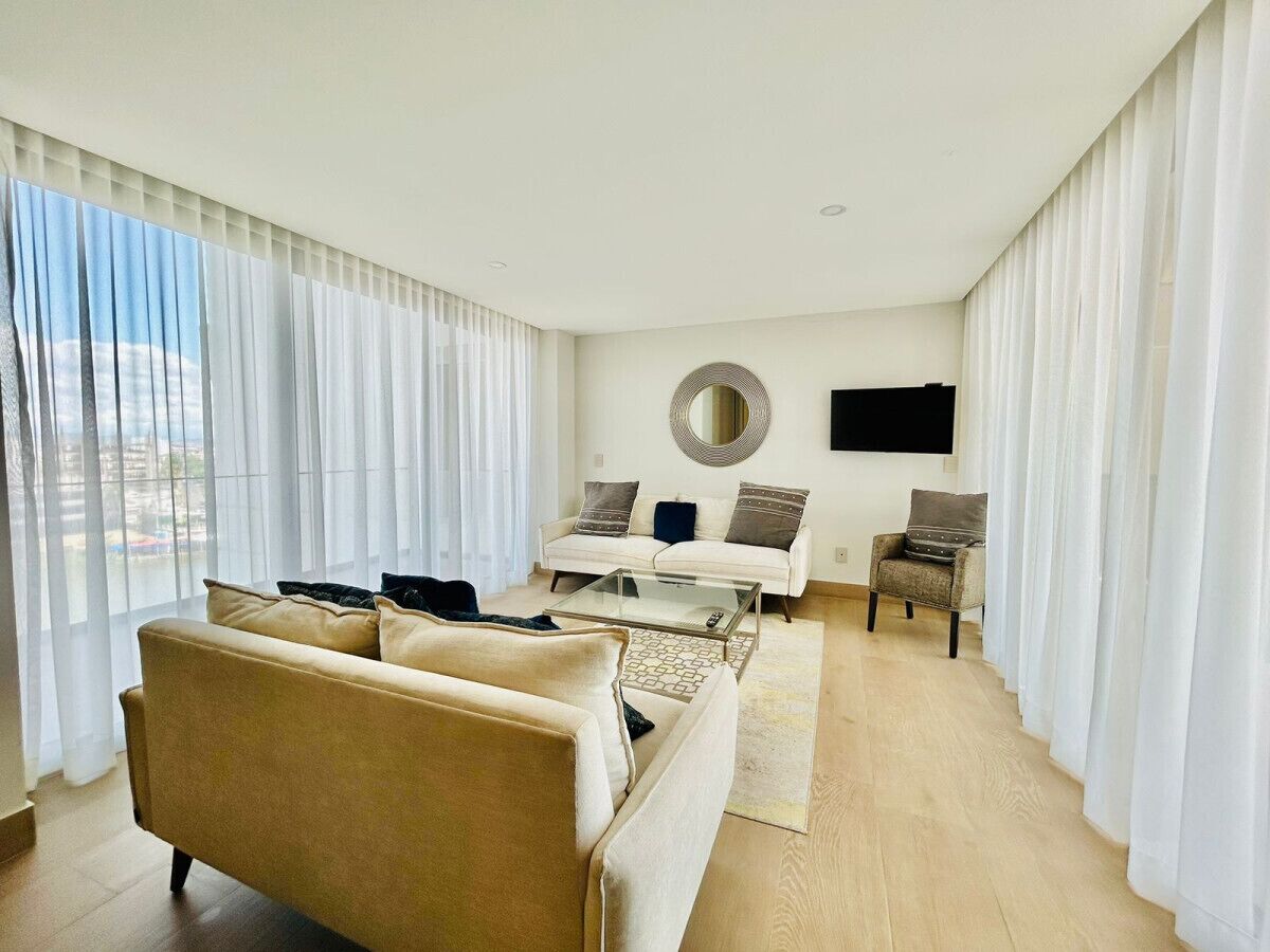 A modern living room with a sofa, armchairs, a coffee table, and a TV.
