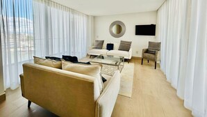 A modern living room with a sofa, armchairs, a coffee table, and a TV.