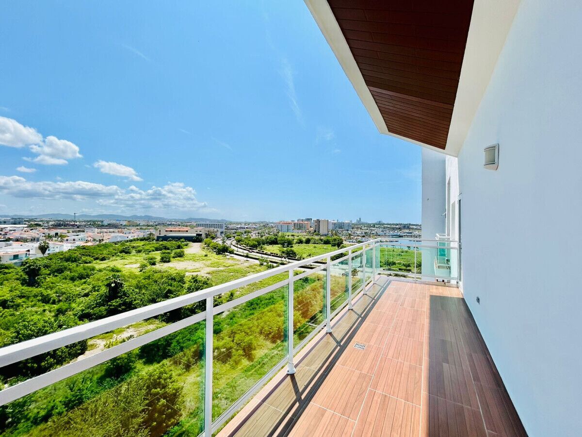 A balcony with a view of a cityscape and greenery.