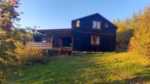 Uma casa de dois andares com telhado vermelho e varanda coberta.