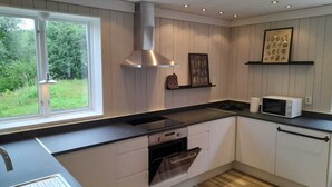 Uma cozinha moderna com bancada preta, armários brancos, exaustor de aço inoxidável e micro-ondas no balcão.