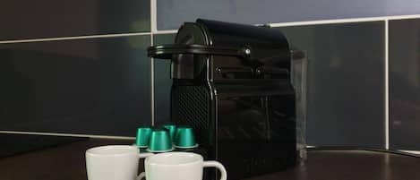 A coffee maker with two white mugs labeled "NESPRESSO" on a kitchen counter.