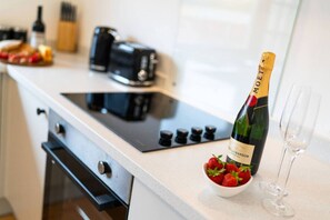 A kitchen with a bottle of champagne, a bowl of strawberries, and two wine glasses on the counter. - Ellaburn - 3 bed w/ parking (Angus)