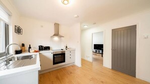 Una cucina moderna con forno a incasso, lavello in acciaio inossidabile e una porta grigia sullo sfondo.