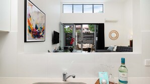 Een moderne keuken met een groot raam, een zithoek met een bank en een woonkamer met een televisie.