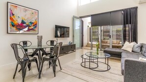 Een moderne woonkamer met een eethoek, een flatscreen-televisie en een groot abstract schilderij.