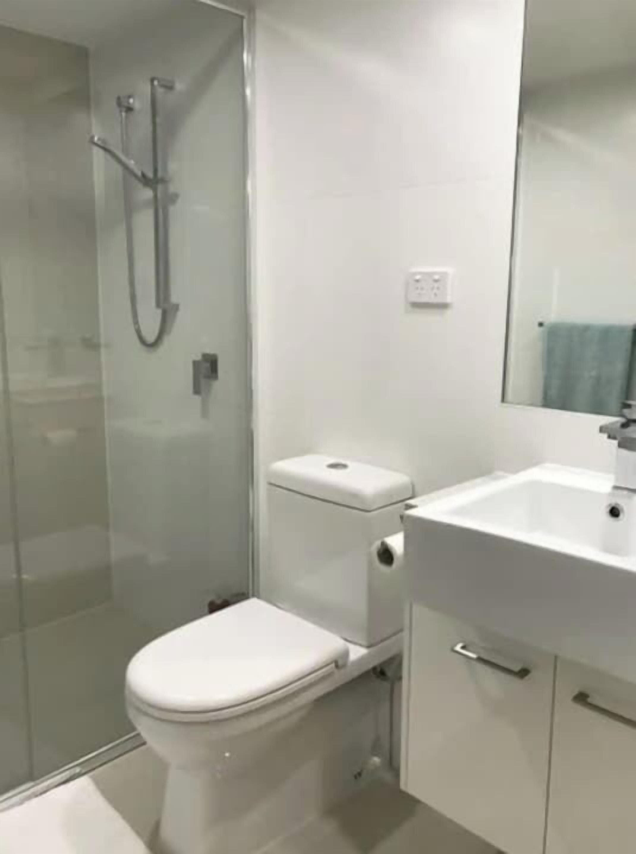 A modern bathroom with a toilet, shower, and sink.