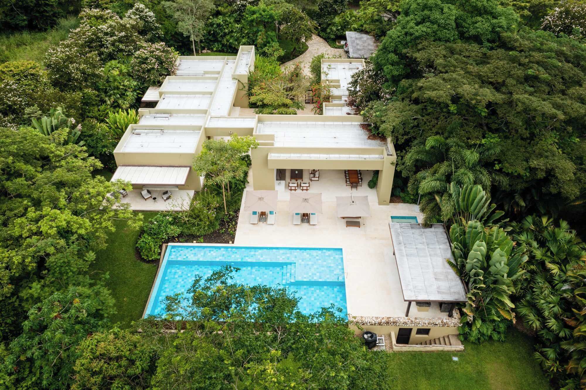 A multi-story building with a swimming pool, surrounded by lush greenery.
