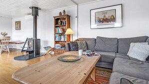 Una sala de estar acogedora con una mesa de centro de madera, un sofá gris, una estantería y una fotografía familiar enmarcada en la pared.