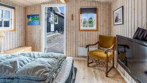 Una habitación acogedora con cama, sillón, televisión y ventana con vista a la calle.