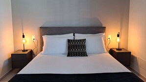 A neatly made bed with white linens, a patterned pillow, and two bedside lamps on nightstands. - New spacious three-room apartment in Viganello (Urban 8) (Lugano)