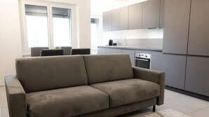 A modern living room with a beige sofa, a small rug, and a kitchen in the background. - Cosy bilo close to the centre (Urban 2) (Lugano)