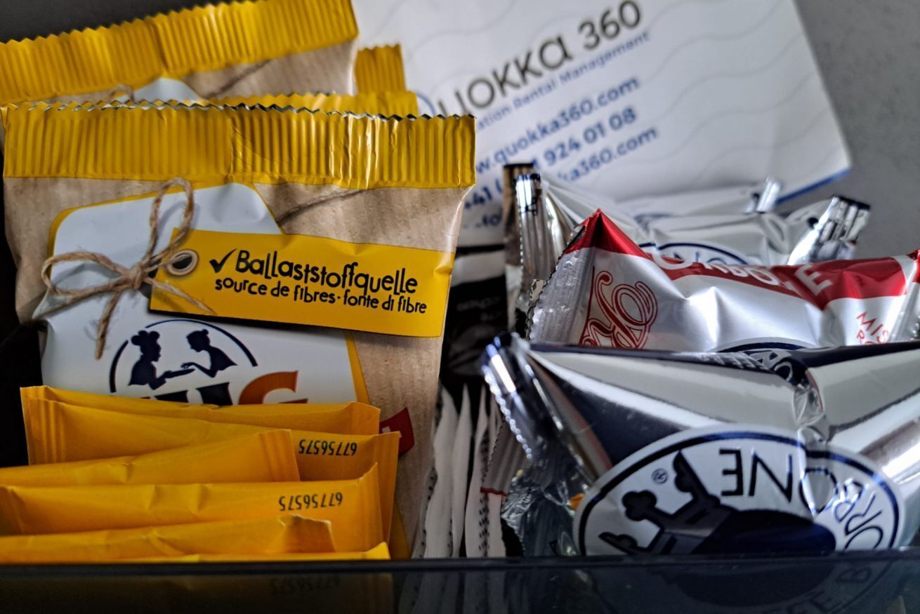 Un ensemble de sacs dotés d’étiquettes jaunes et blanches, dont certains sont attachés avec de la ficelle, ainsi qu’une feuille de papier blanche portant un texte imprimé et un logo.