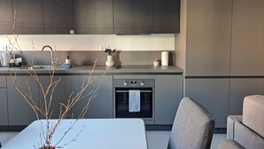 Una cocina moderna con armarios oscuros, horno empotrado y comedor con mesa y sillas.