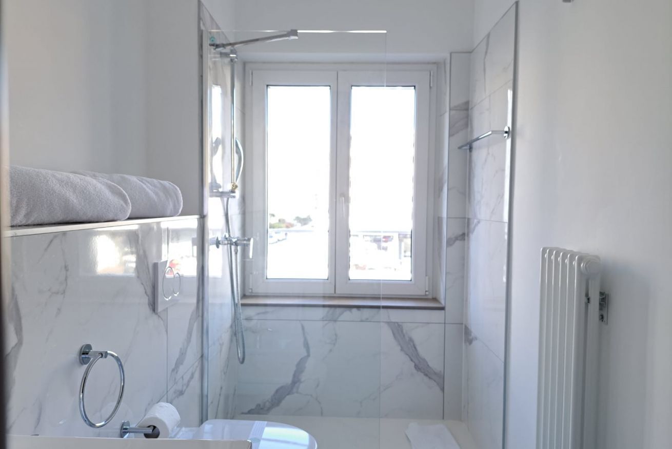 Une salle de bain moderne dotée d’une grande fenêtre, d’une baignoire, d’une douche et d’un porte-serviettes.