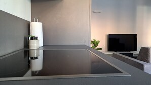 Una cocina moderna con una isla central, un televisor de pantalla plana y una pequeña planta.