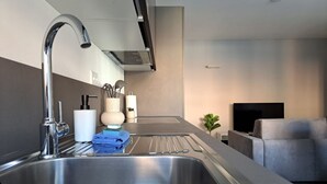 Una cocina moderna con un lavamanos de acero inoxidable, una estufa empotrada y un televisor de pantalla plana al fondo.