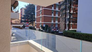Un balcone con vista aperta su un edificio a più piani con facciata in mattoni rossi e infissi verdi.