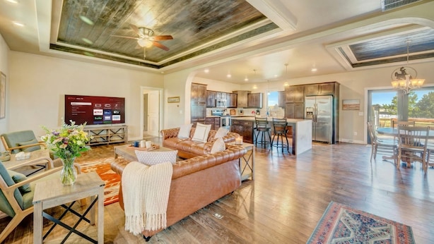 A spacious living area with a leather sofa, wooden flooring, and a ceiling fan.
