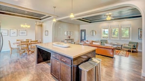 A spacious kitchen with a large island, wooden cabinets, and a dining area with chairs.