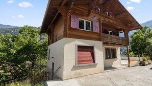 A wooden chalet with a balcony, a red shuttered window, and a view of the surrounding landscape. - Pretty chalet-style studio (Euseigne)