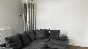A sectional sofa with multiple cushions in a room with white walls and a radiator.