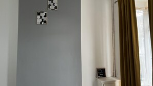 A room with a grey wall, a window with brown curtains, and two framed abstract art pieces.