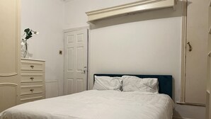 A bedroom with a bed, dresser, and a door.