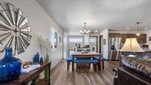 Uma cozinha moderna com área de refeições, piso de madeira e uma grande peça decorativa na parede.