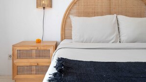 Une chambre à coucher avec une tête de lit ronde en osier, une table de chevet avec une lampe et un lit avec deux oreillers.