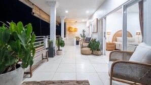 Un balcon spacieux agrémenté de plantes en pot, de meubles en osier et offrant une vue sur la mer.