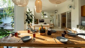 Un coin repas avec une table en bois dressée pour le repas, entourée de lanternes en papier suspendues.