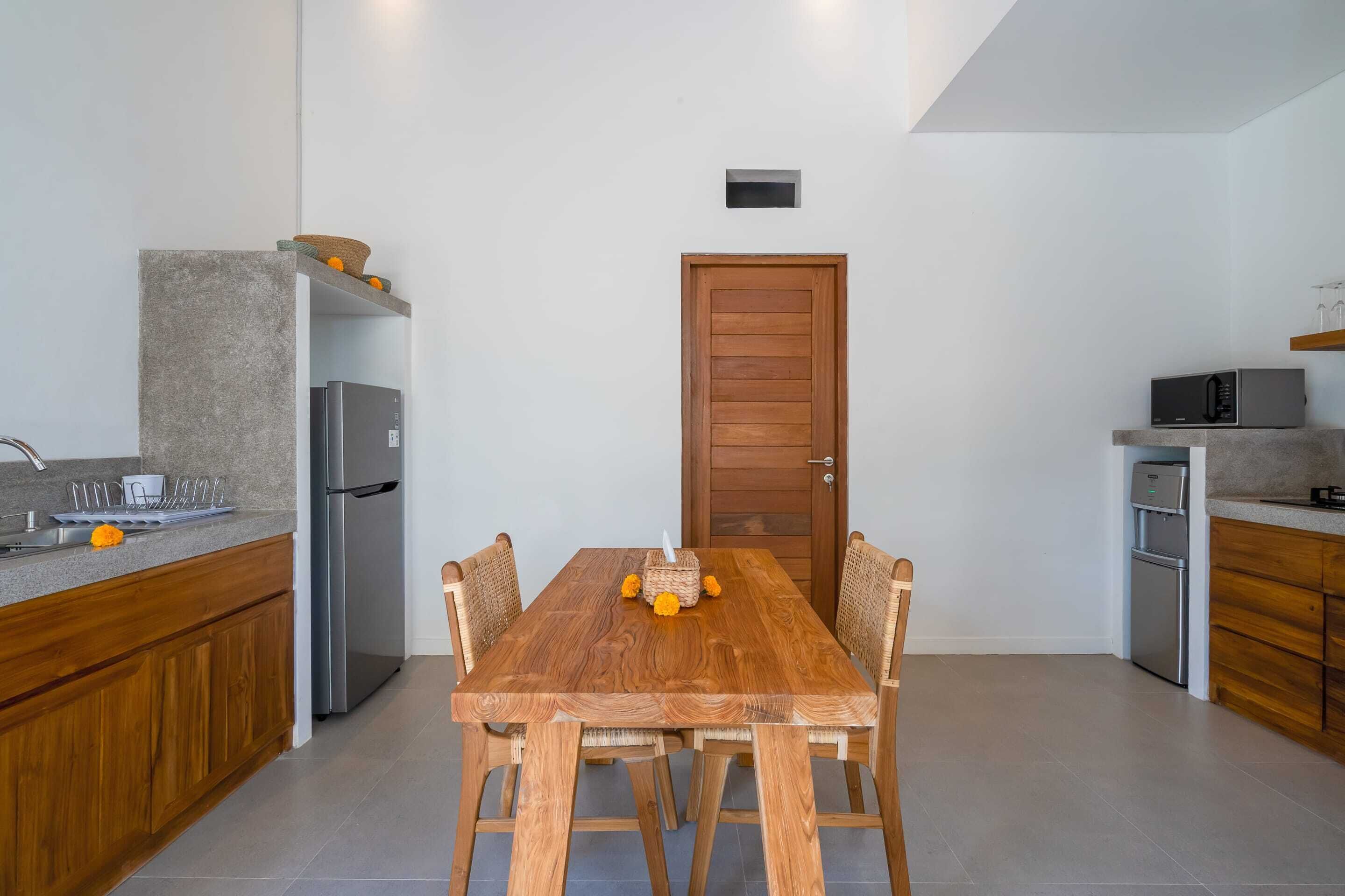 A modern kitchen with a wooden dining table, built-in appliances, and a clean, minimalist design.