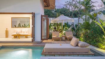 A poolside area with a sofa, chairs, and a table.