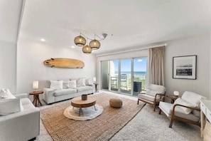 A modern living room with a sofa, chairs, a coffee table, and a large window with a view.