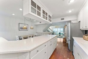 A modern kitchen with white cabinetry, a central island, and a view to a balcony.