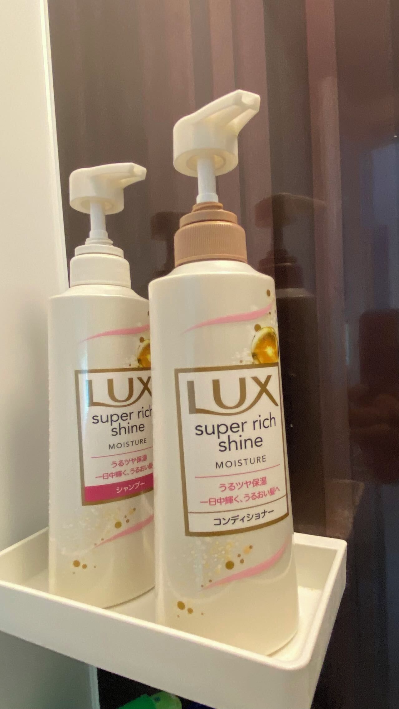 Two bottles of 'LUX super rich shine' moisture on a white shelf.