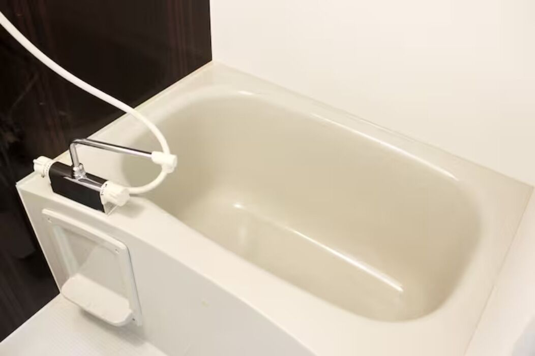 A white bathtub with a control panel and a white towel rack.