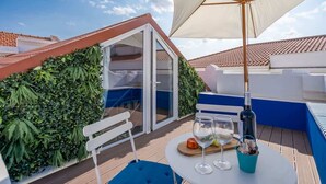 Eine Dachterrasse mit Tisch, Stühlen und einem großen Sonnenschirm.