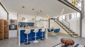Eine moderne Küche mit einer zentralen Kochinsel, Barhocker und einer Treppe, die in eine obere Ebene führt.