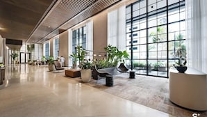 A spacious lobby with large windows, seating areas, and potted plants. - Chic & Cozy Downtown Miami Studio | City Views (Miami)