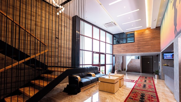 A modern lobby with a staircase, a black leather sofa, a wooden coffee table, and a patterned carpet. - HOTEL MANGALA TEMPLE VIEW (Chavakkad)