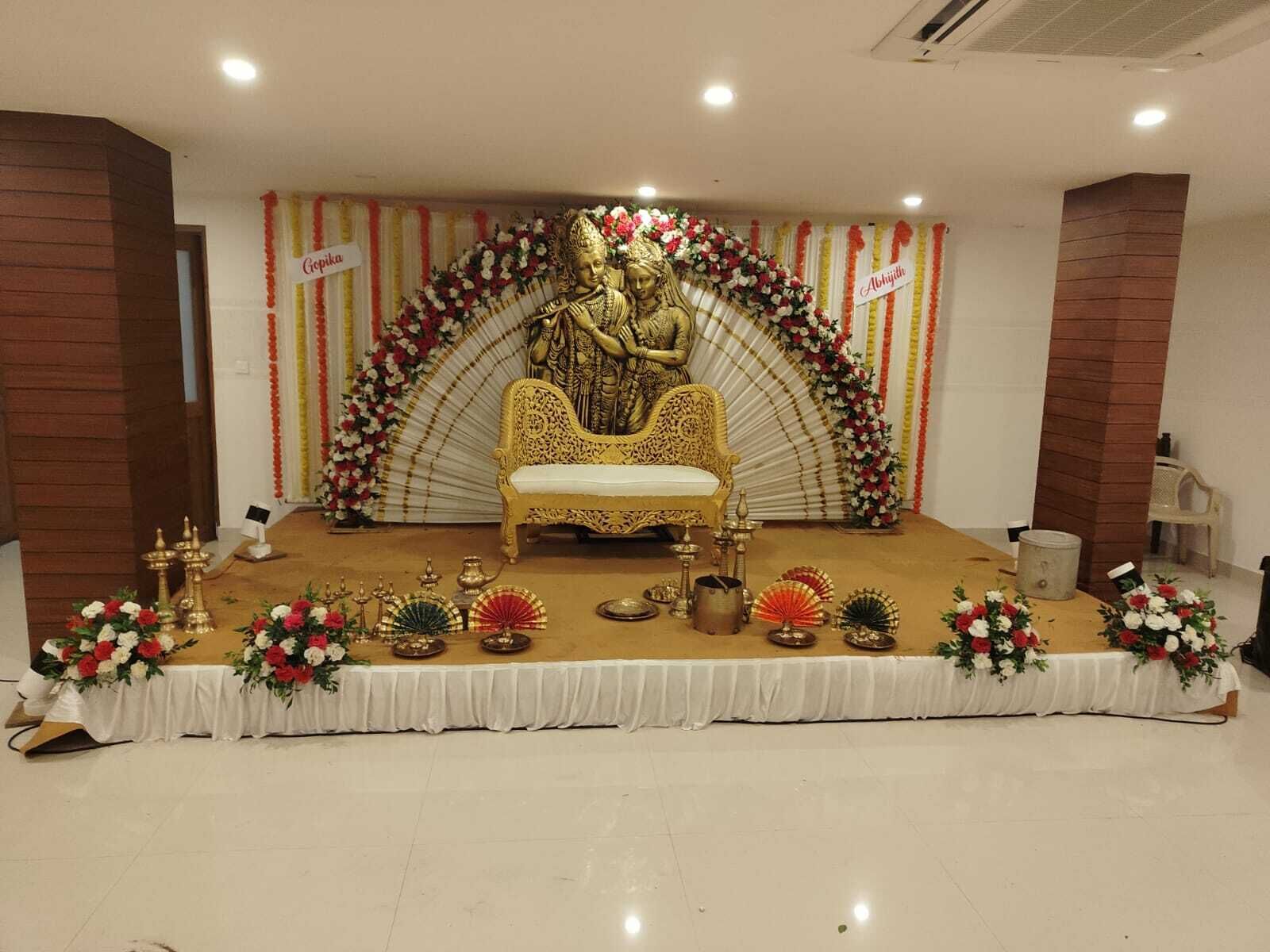 Un escenario con un trono dorado, adornos florales y artefactos tradicionales indios.