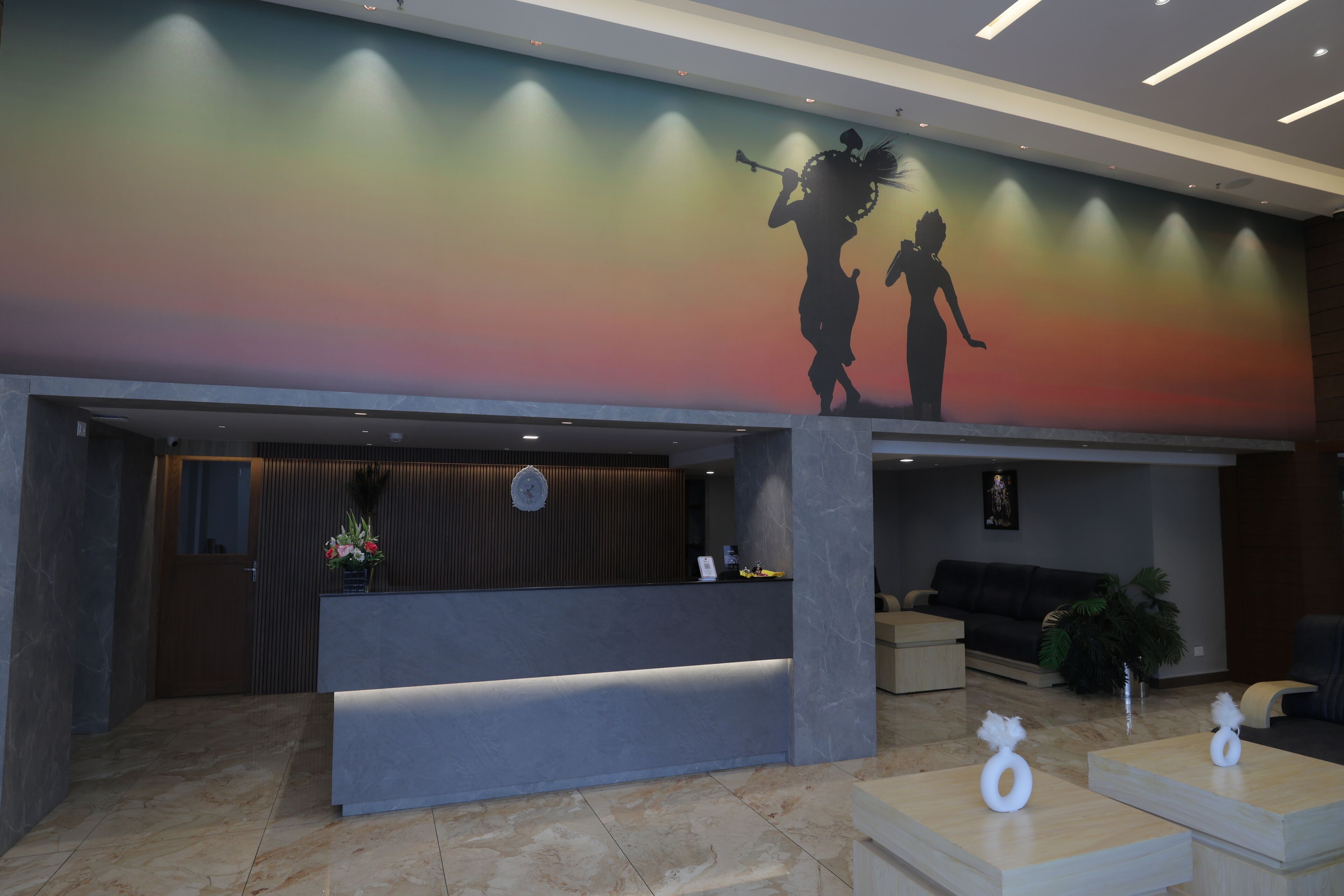 A reception area with a modern design, including a reception desk, seating area, and a colorful mural on the wall.