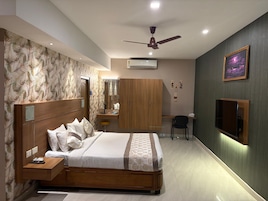 Un dormitorio moderno con cama, mesita de noche, armario, tocador y televisor.