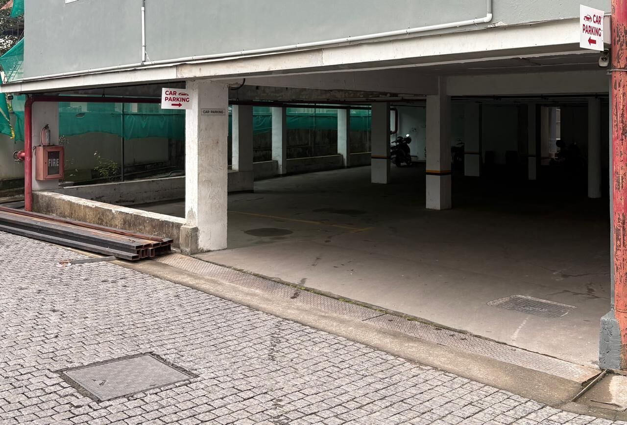 Entrada a un aparcamiento con carteles que indican 'CAR PARKING', un extintor y una motocicleta en el interior.