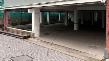 Entrada a un aparcamiento con carteles que indican 'CAR PARKING', un extintor y una motocicleta en el interior.