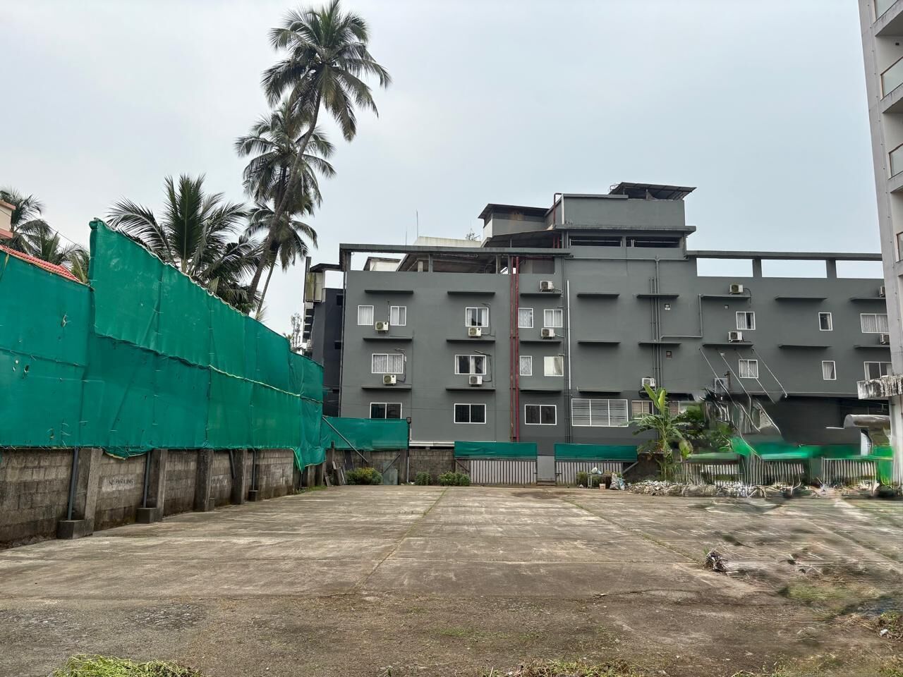 Un edificio de varios pisos con fachada gris, unidades de aire acondicionado y una entrada con portón.